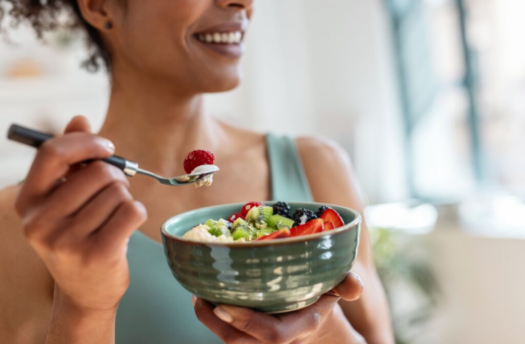 A person holding a bowl of food, eating after a dental cleaning.
