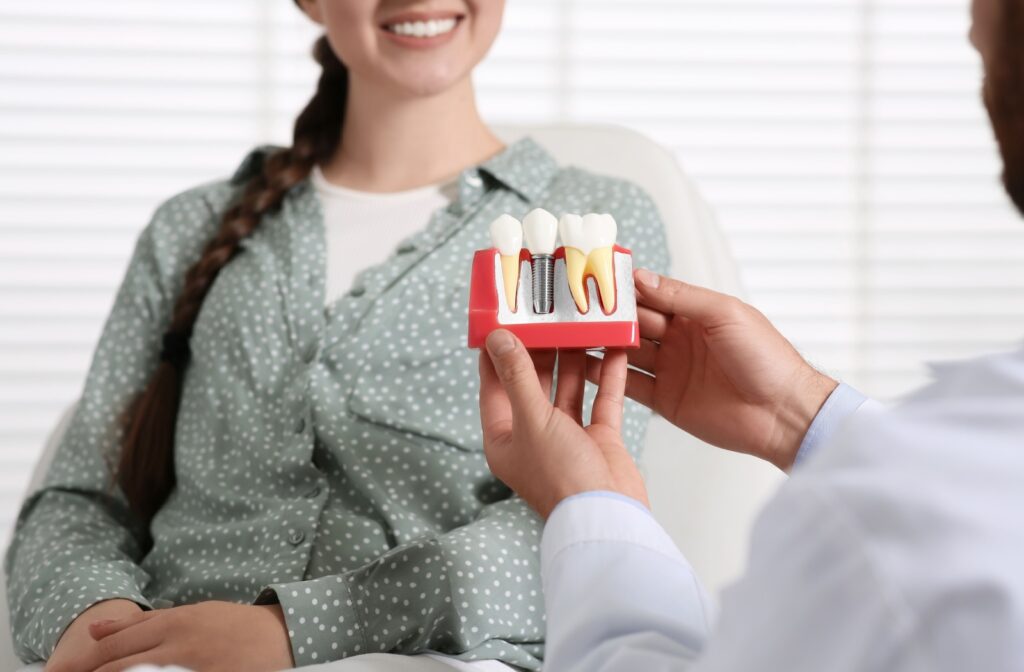 A person talking with a dentist who is holding a diagram of a dental implant