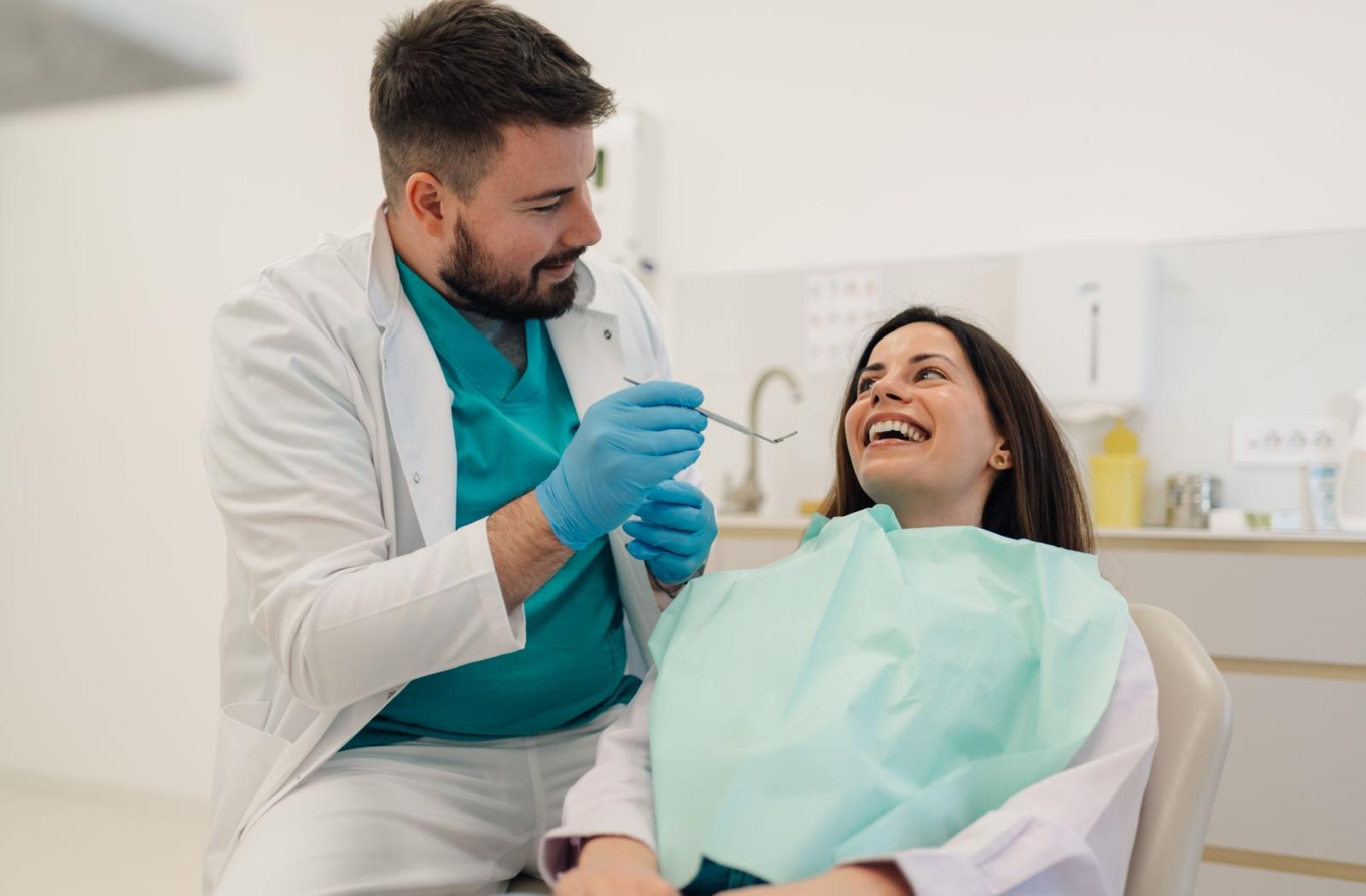 A dentist talking to a patient while holding a dental tool