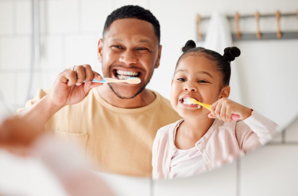 A father and his child brushing their teeth in the mirror in the morning