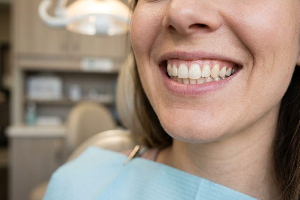 Close-up of a smiling adult patient wearing a dental bib in a dental clinic, showing their teeth.